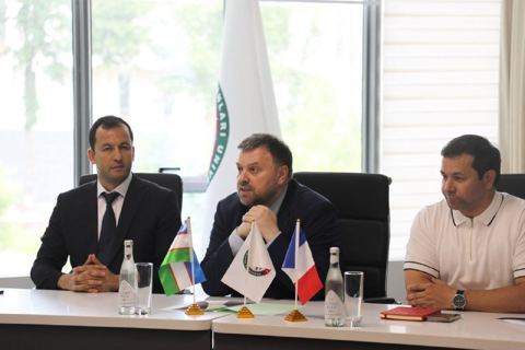 Speakers at a table with Uzbek and French flags